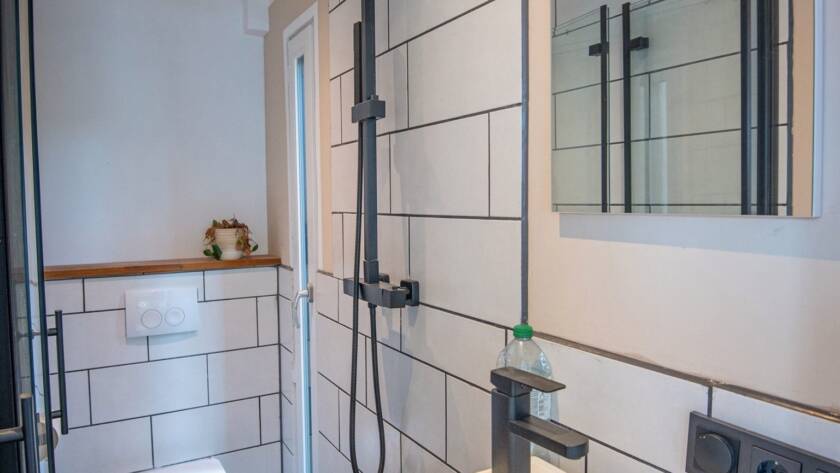 Fertiger Sanitärraum in einem Raummodul mit Regendusche, Wand-WC, Waschtisch und Spiegel