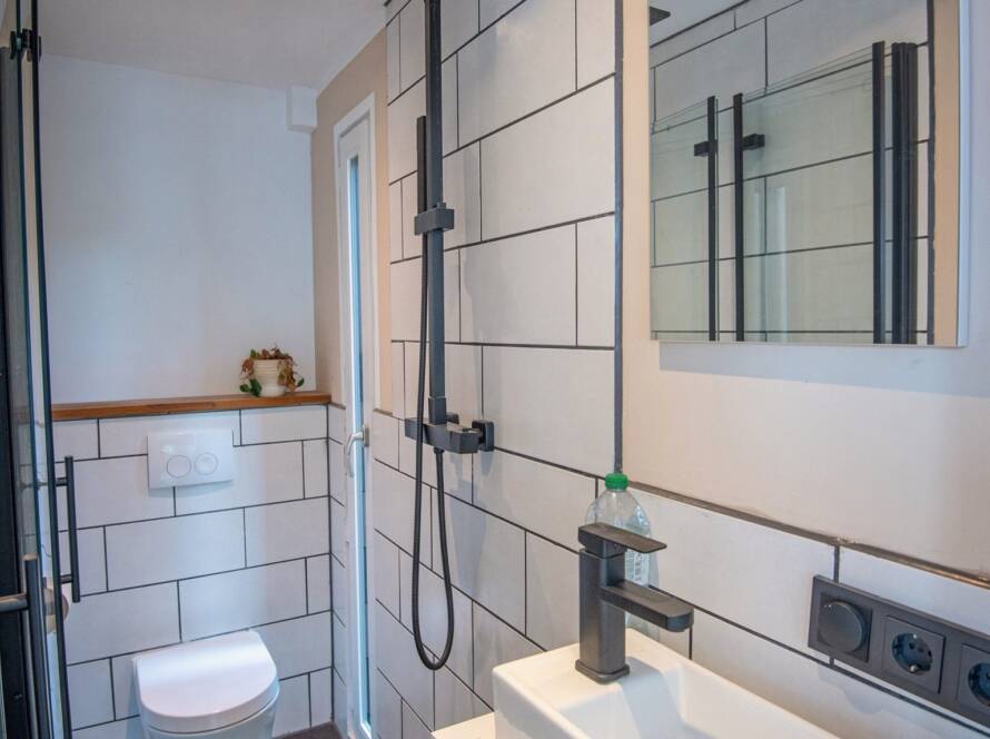 Fertiger Sanitärraum in einem Raummodul mit Regendusche, Wand-WC, Waschtisch und Spiegel