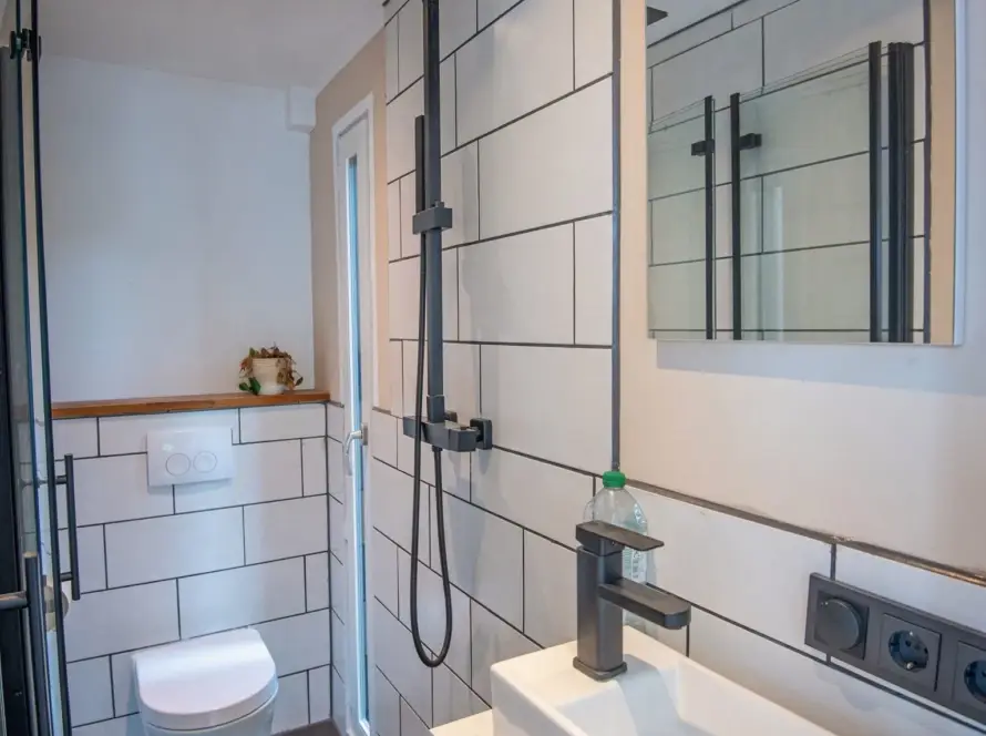 Fertiger Sanitärraum in einem Raummodul mit Regendusche, Wand-WC, Waschtisch und Spiegel