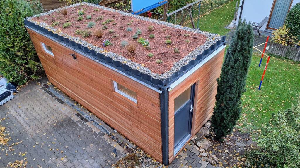 Gartenhaus 15 m² von Contain-us – Außenansicht mit begrüntem Dach auf einer gepflasterten Fläche