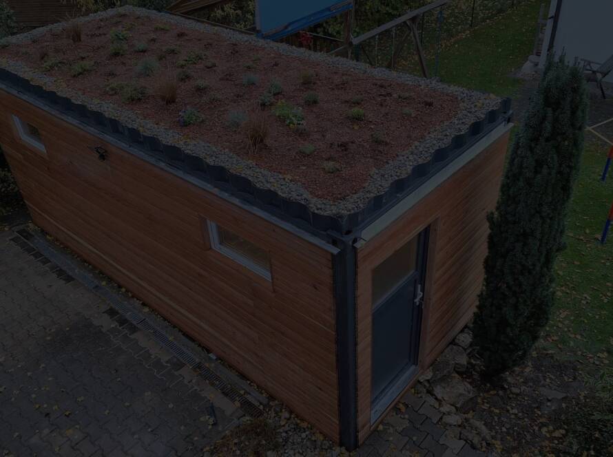 Gartenhaus 15 m² von Contain-us – Außenansicht mit begrüntem Dach auf einer gepflasterten Fläche