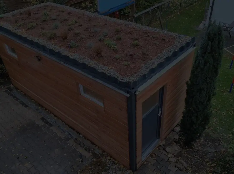 Gartenhaus 15 m² von Contain-us – Außenansicht mit begrüntem Dach auf einer gepflasterten Fläche