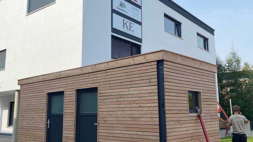 Gartenhaus 15 m² von Contain-us – das Modul steht auf Rangierrollen vor einem Wohnhaus und wird an seinen Platz geschoben