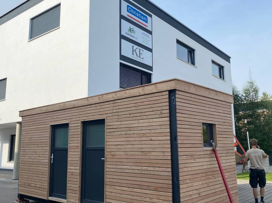 Gartenhaus 15 m² von Contain-us – das Modul steht auf Rangierrollen vor einem Wohnhaus und wird an seinen Platz geschoben