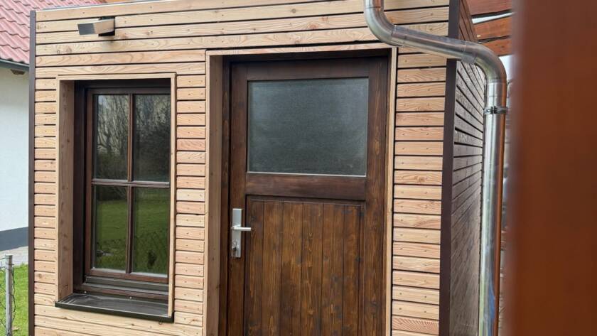 Gartenhaus 7 m² von Contain-us – Außenansicht mit Tür und Fenster, daneben ein Fallrohr