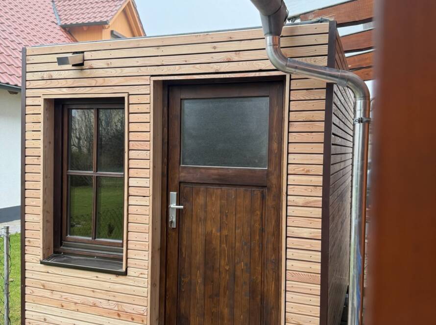 Gartenhaus 7 m² von Contain-us – Außenansicht mit Tür und Fenster, daneben ein Fallrohr