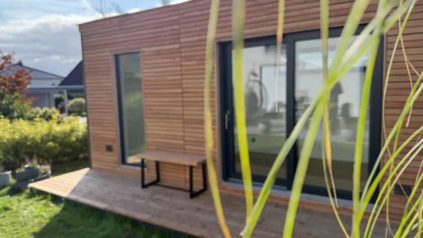 Heimkino 15 m² von Contain-us – Außenansicht mit Holzfassade und vorgelagerter Terrasse im Garten
