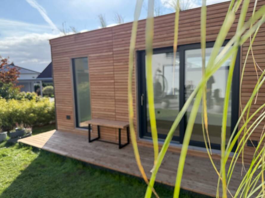 Heimkino 15 m² von Contain-us – Außenansicht mit Holzfassade und vorgelagerter Terrasse im Garten