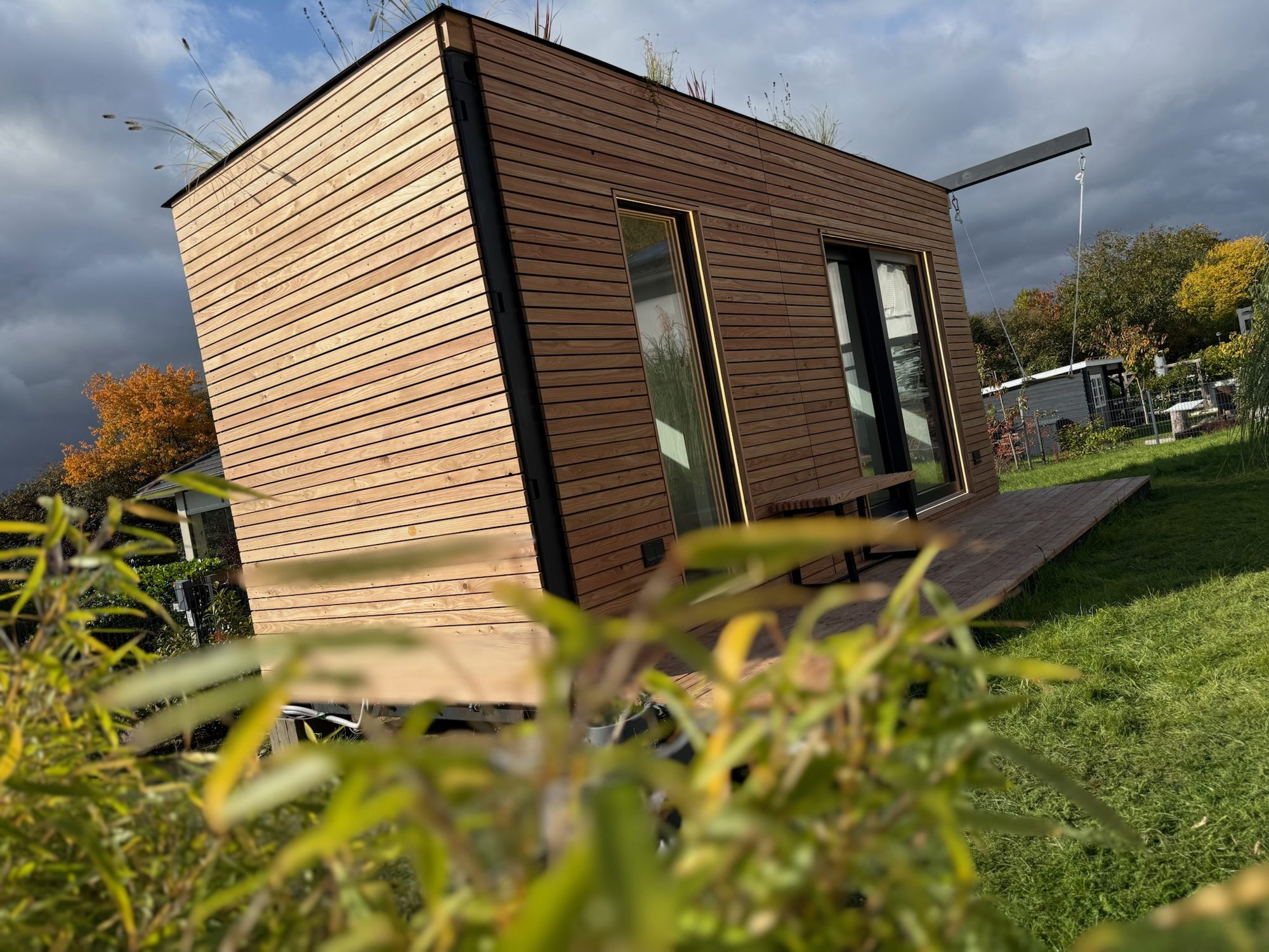 Heimkino 15 m² von Contain-us – Außenansicht der Gebäudeecke mit Holzfassade und dunklem Sockel