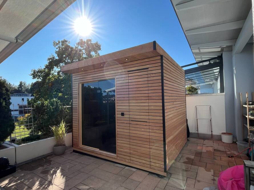 Sauna 7 m² von Contain-us – Außenansicht neben dem Wohnhaus, Glasfront zum Garten
