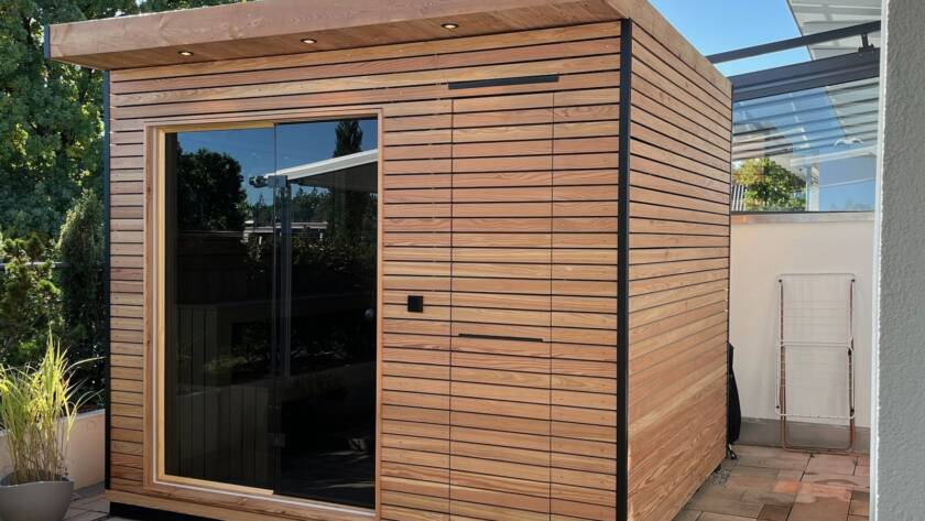 Sauna 7 m² von Contain-us – Außenansicht der freistehenden Gartensauna mit Panoramafenster und Holzfassade