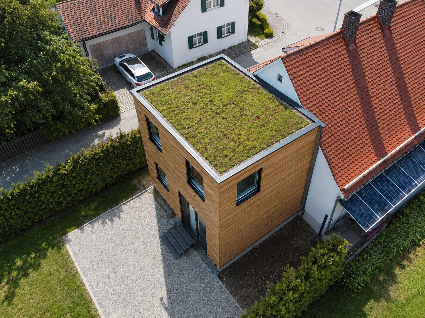 Hausanbau 60 m² von Contain-us – Luftaufnahme des begrünten Dachs neben dem Ziegeldach des Bestandshauses