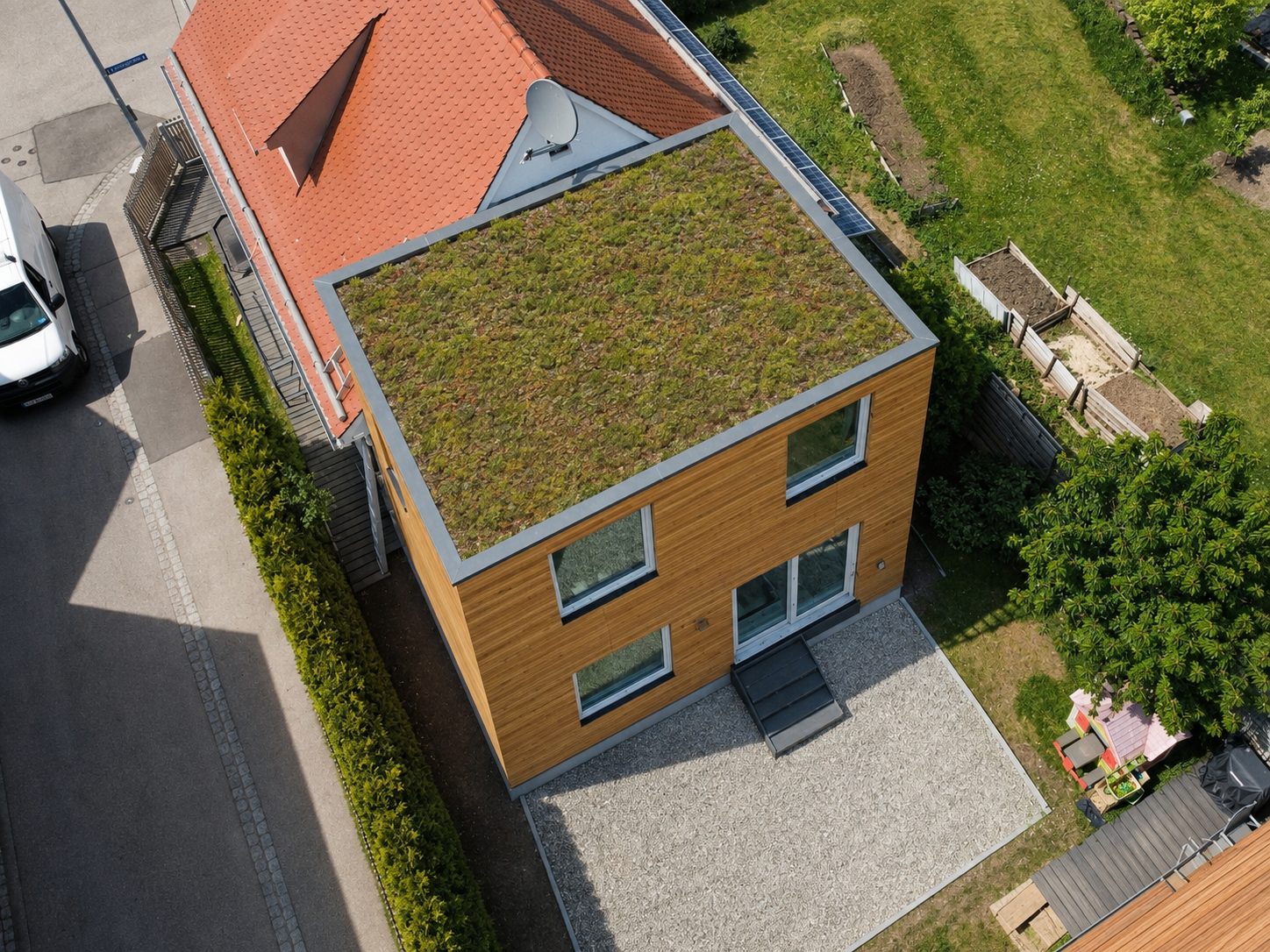 Hausanbau 60 m² von Contain-us – Luftaufnahme des begrünten Dachs, daneben Straße und Nachbarbebauung