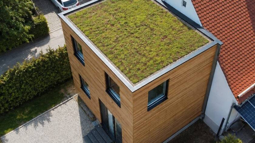 Hausanbau 60 m² von Contain-us – Luftaufnahme des begrünten Dachs neben dem Ziegeldach des Bestandshauses
