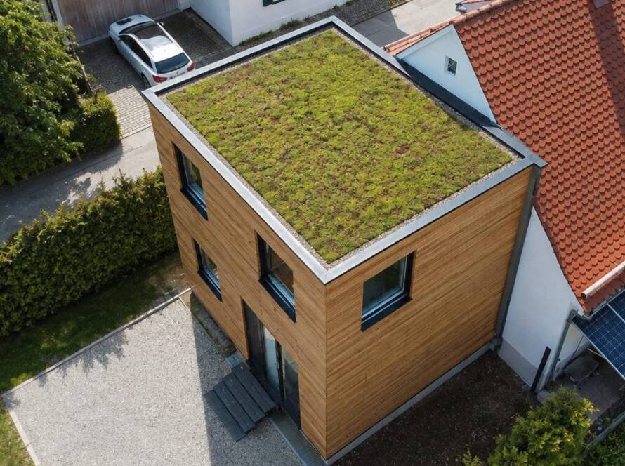 Hausanbau 60 m² von Contain-us – Luftaufnahme des begrünten Dachs neben dem Ziegeldach des Bestandshauses