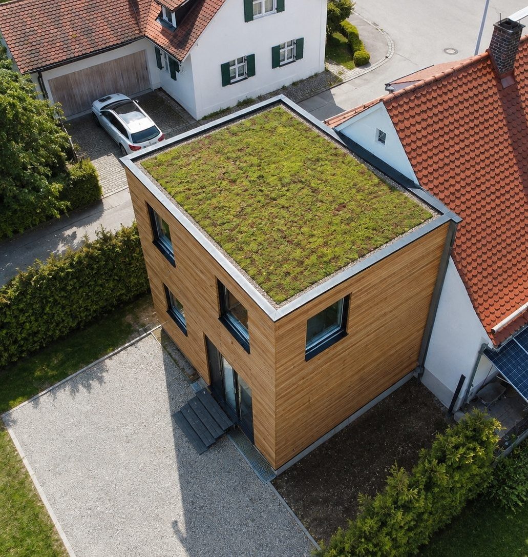 Hausanbau 60 m² von Contain-us – Luftaufnahme des begrünten Dachs neben dem Ziegeldach des Bestandshauses
