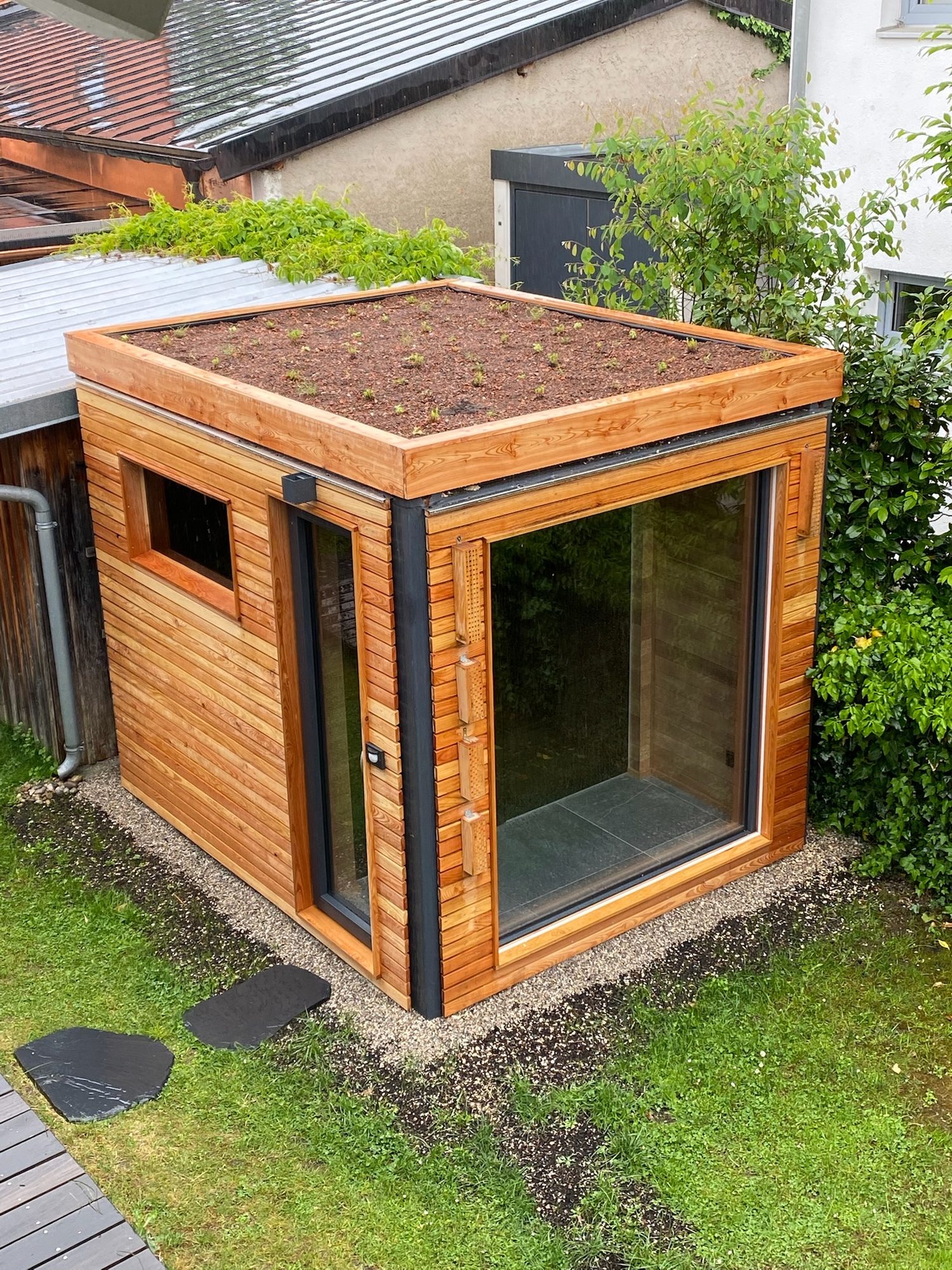 Sauna 7 m² von Contain-us – Ansicht von oben auf das begrünte Dach, Trittplatten führen zum Eingang