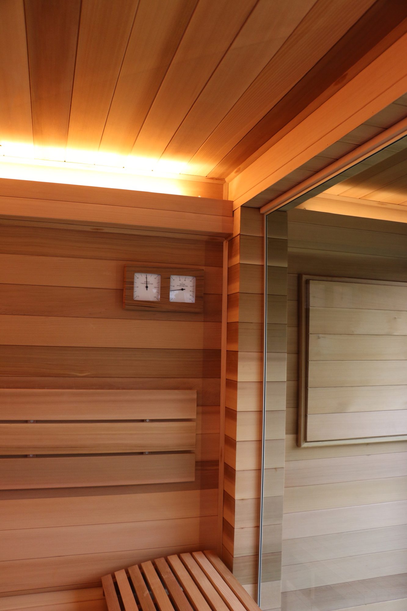 Sauna 7 m² von Contain-us – Blick von der Bank zur Glastür, Lichtband entlang der Deckenkante
