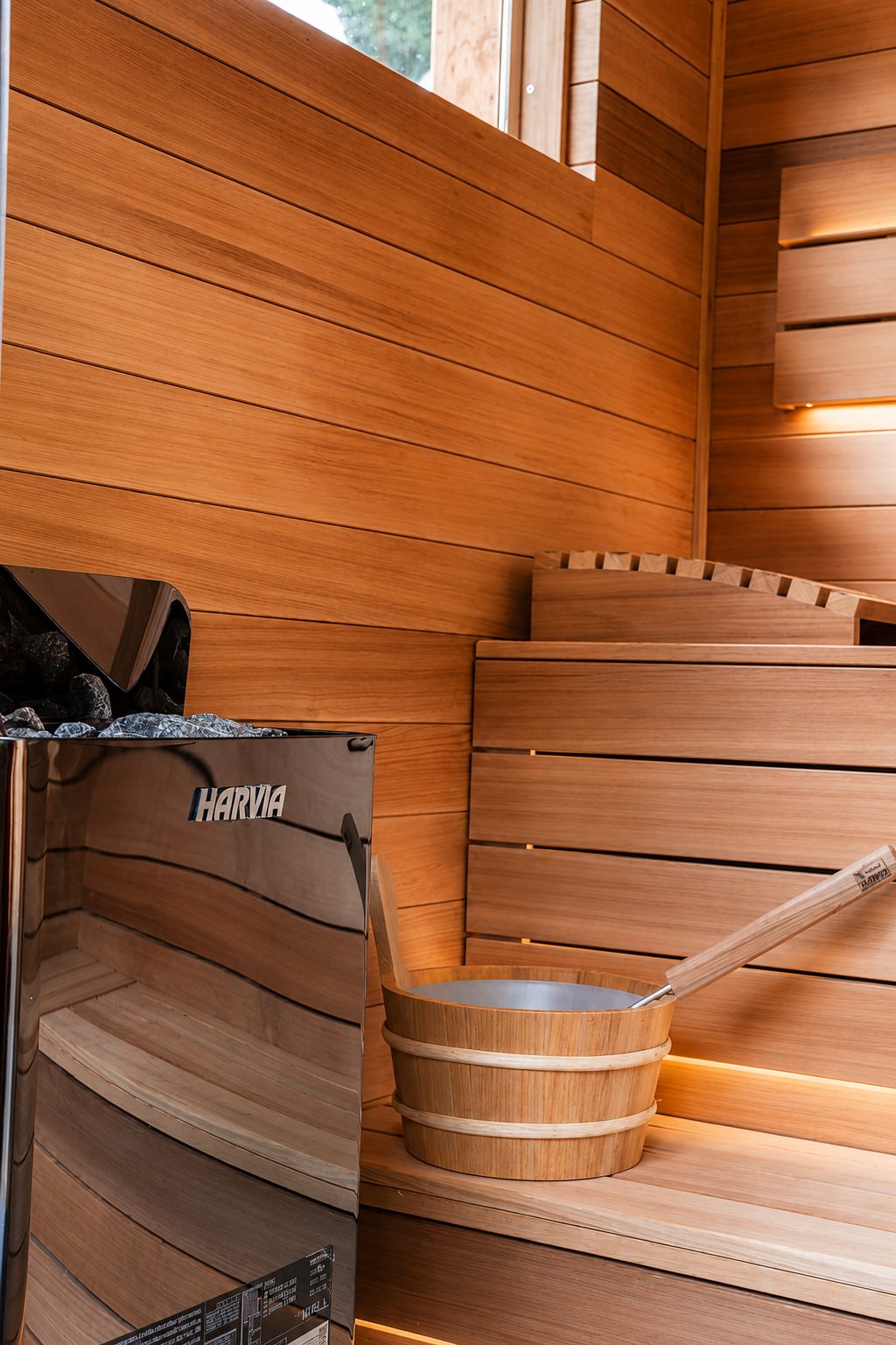 Sauna 7 m² von Contain-us – Saunaofen mit Holzkübel und Kelle vor der Rückwand