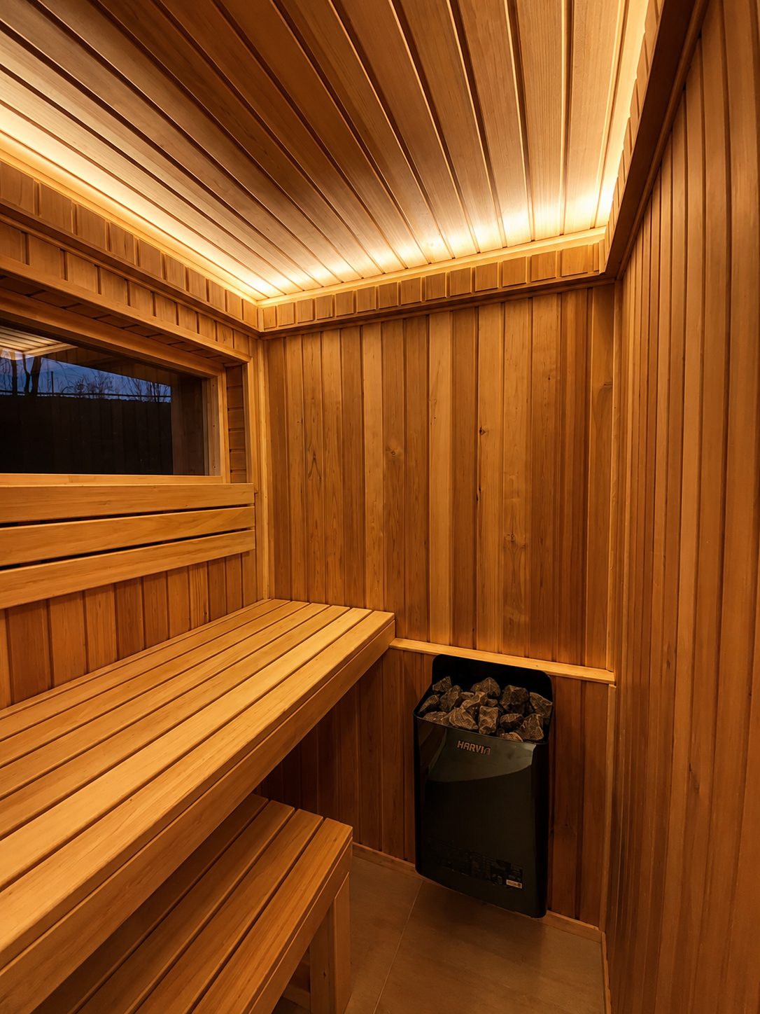 Sauna mit Büro 15 m² von Contain-us – Saunabank aus hellem Holz mit Ofen und indirekter Beleuchtung