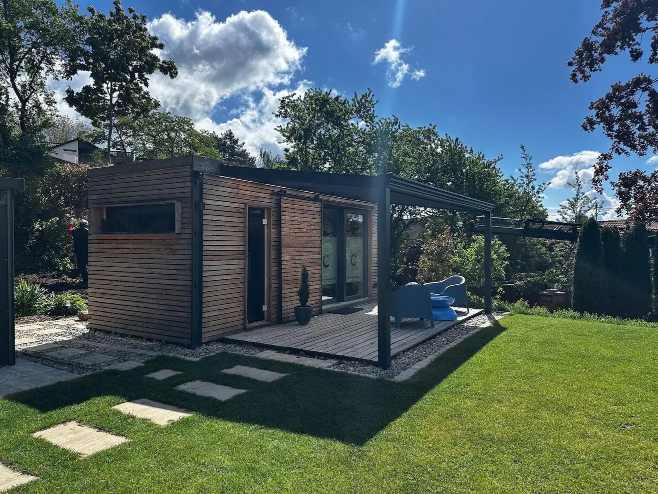 Sauna mit Büro 15 m² von Contain-us – Außenansicht mit Glasfront, davor eine gepflasterte Terrasse