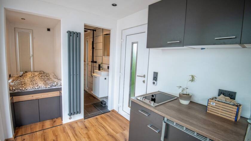 Tiny House 15 m² von Contain-us – Innenraum mit Küchenzeile, Holzboden und Blick zur Schlafnische