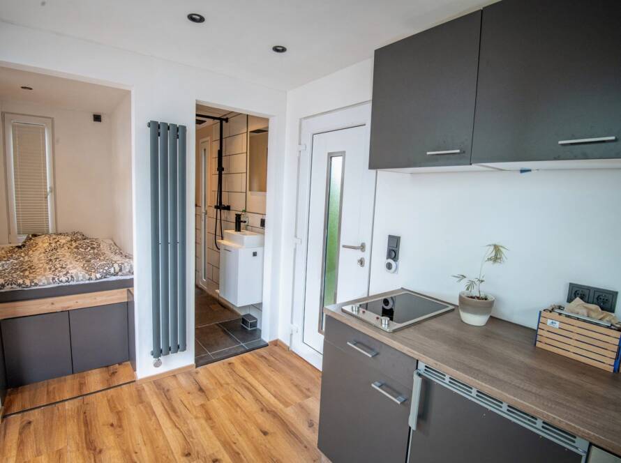 Tiny House 15 m² von Contain-us – Innenraum mit Küchenzeile, Holzboden und Blick zur Schlafnische