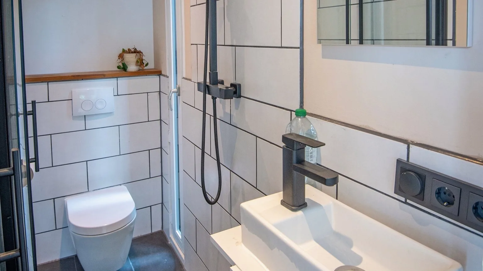 Badezimmer im Modulhaus mit bodengleicher Dusche, Wandhänge-WC und weißen Metrofliesen