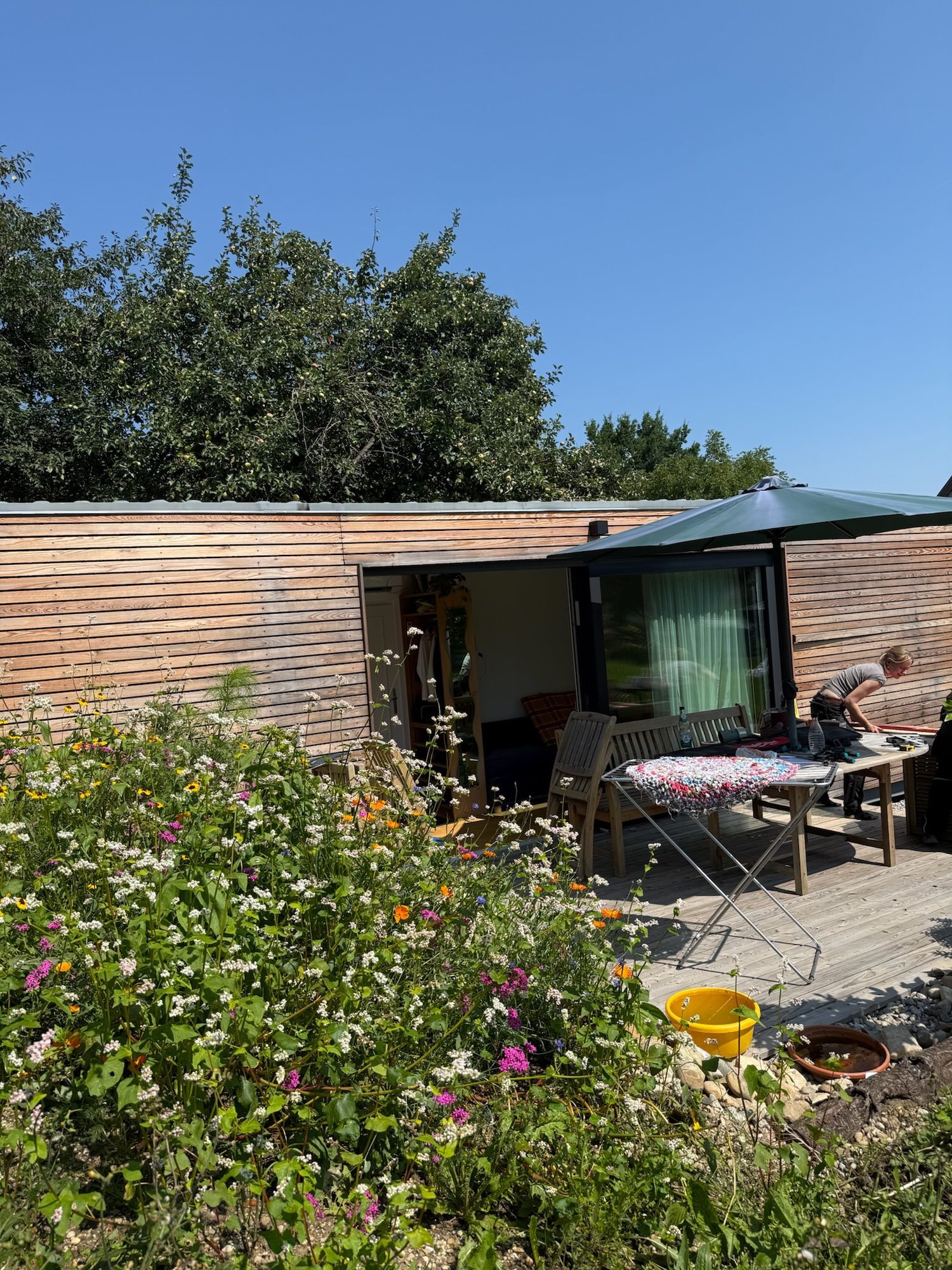 Tiny House 30 m² von Contain-us – Außenansicht mit Terrasse, Sitzgruppe und Blumenbeet