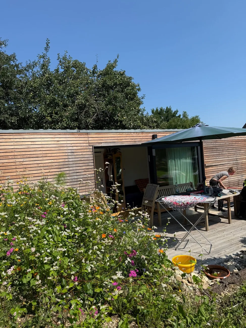 Tiny House 30 m² von Contain-us – Außenansicht mit Terrasse, Sitzgruppe und Blumenbeet