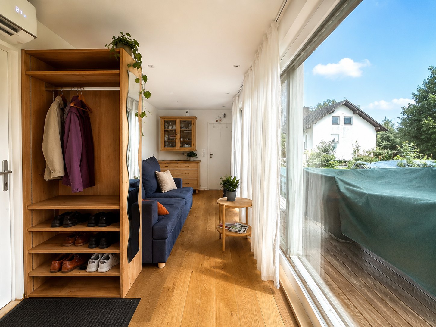 Tiny House 30 m² von Contain-us – Innenraum mit offenem Garderobenschrank und Sitzbereich vor der Fensterfront