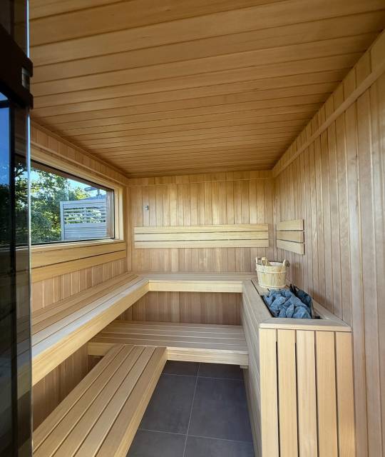Sauna 7 m² von Contain-us – Innenraum mit zweistufiger Bank, Fenster und Saunaofen