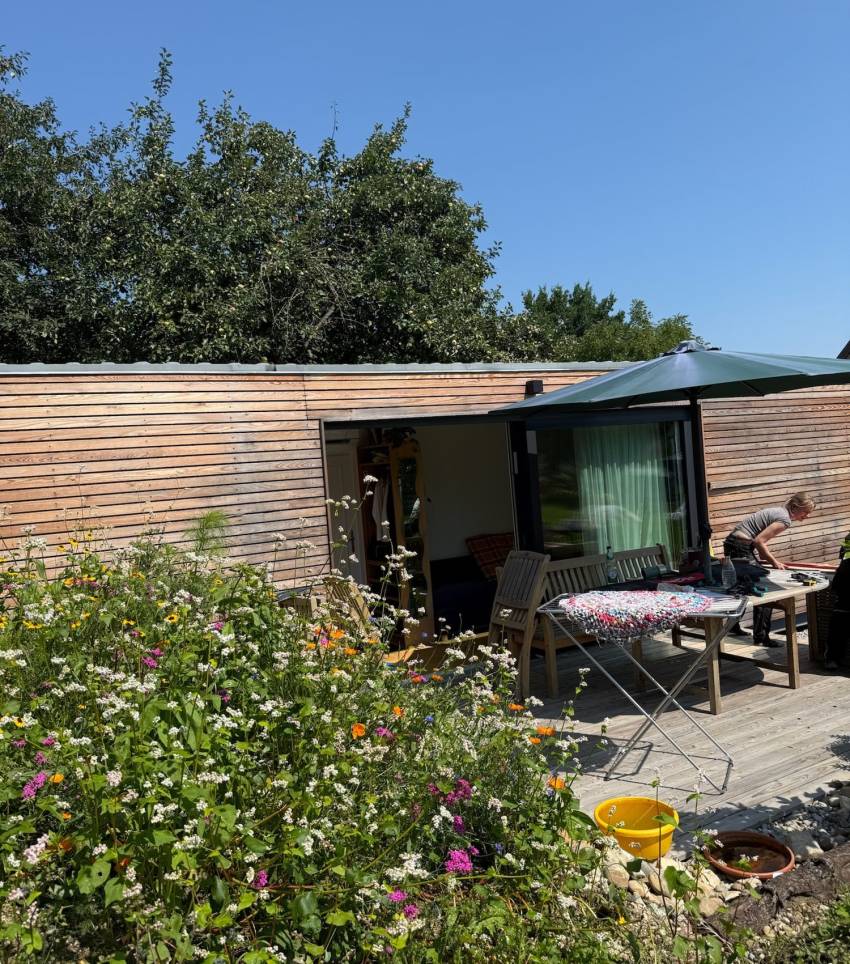 Tiny House 30 m² von Contain-us – Außenansicht mit Terrasse, Sitzgruppe und Blumenbeet