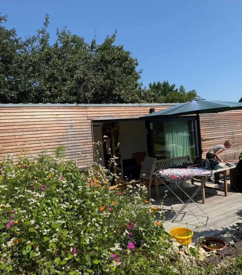 Tiny House 30 m² von Contain-us – Außenansicht mit Terrasse, Sitzgruppe und Blumenbeet